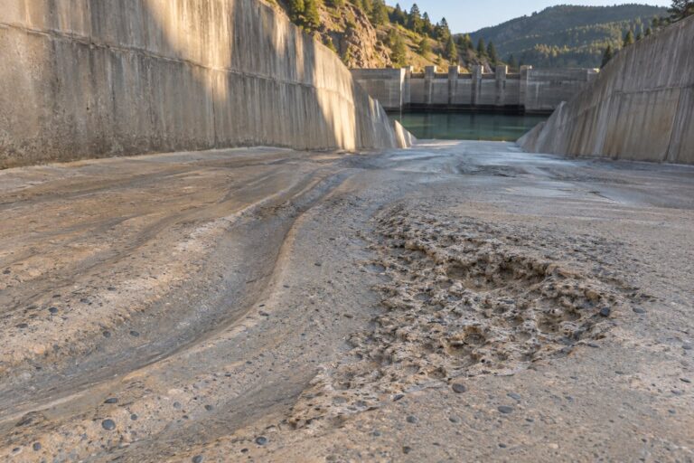 Conceptual inspection view of worn concrete spillway invert with abrasion grooves and localized pitting